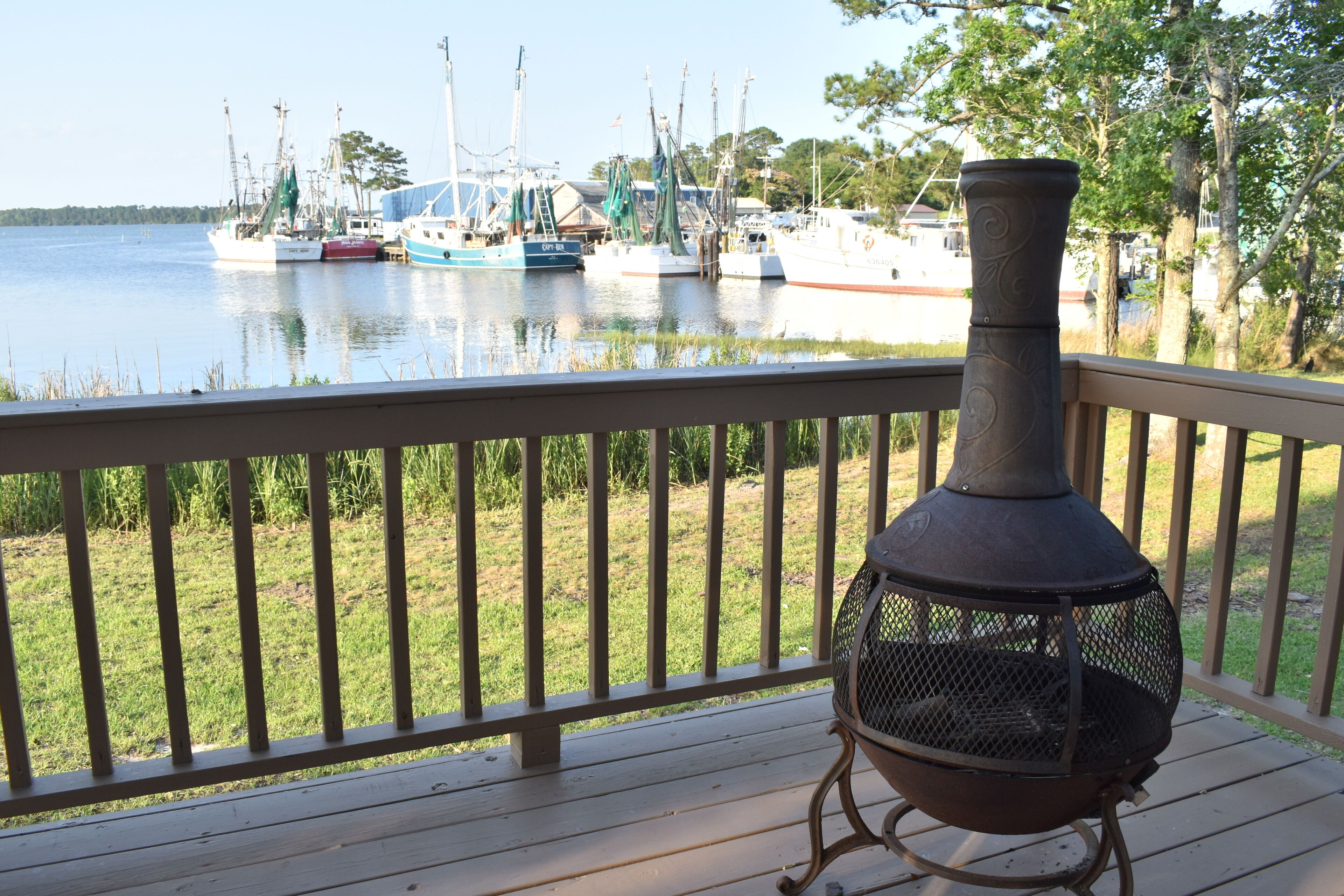 A deck with a metal grill and a view of boats on the water.