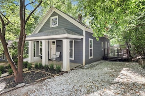 A house with a porch, a deck, and a gravel driveway.