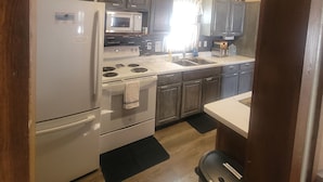 A kitchen with a refrigerator, stove, microwave, and sink. - Four season fun, classic LAKEFRONT cabin for families! (Bigfork)