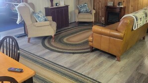 A living room with a television, two armchairs, a sofa, a fireplace, and a wooden ceiling. - Four season fun, classic LAKEFRONT cabin for families! (Bigfork)