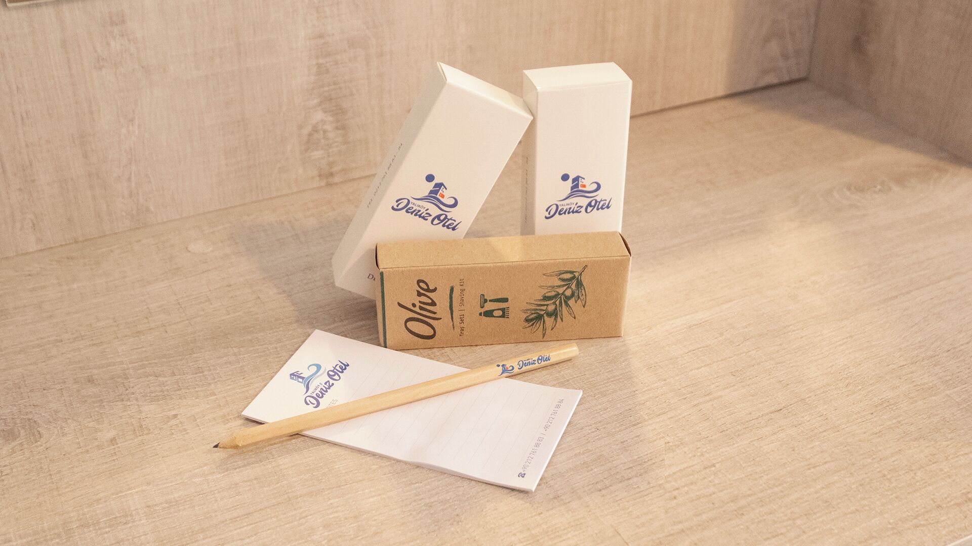 Una superficie di legno con una scatola di cartone etichettata 'Olive' e una matita di legno.