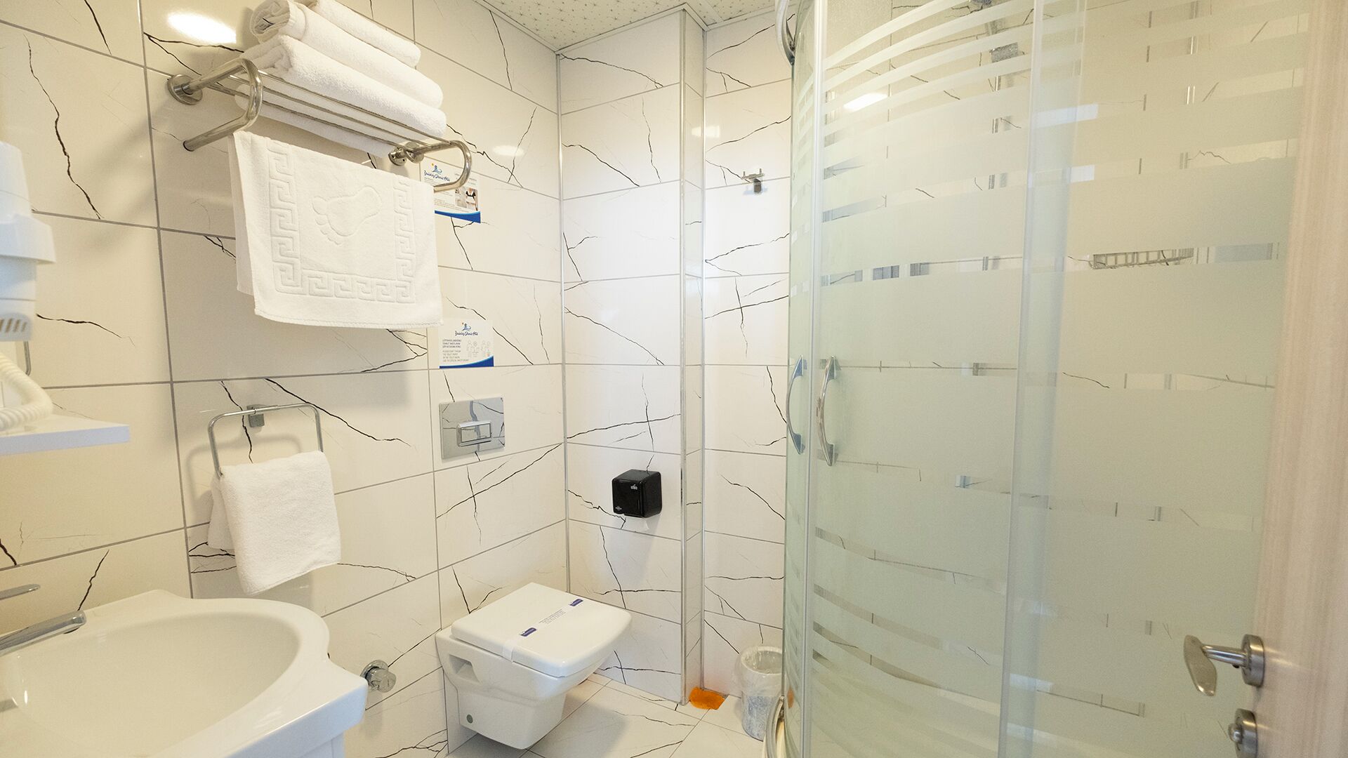 A bathroom with a white sink, toilet, and glass shower enclosure.
