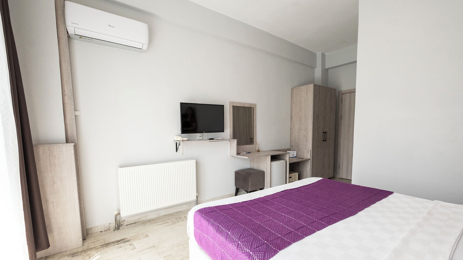 A bedroom with a bed, a TV, a wardrobe, and a radiator.
