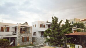 A modern building with stone and white facades, multiple balconies, and a garden area with potted plants. - Studio με θέα θάλασσα και ουρανό!! (Gytheio)