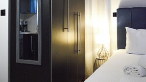 A hotel room with a bed, a wardrobe, a small kitchenette, and a nightstand with a lamp. - Studio με θέα θάλασσα και ουρανό!! (Gytheio)
