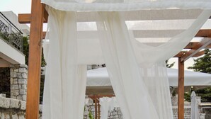 A poolside area with a wooden pergola, white canopies, and stone walls. - Studio με θέα θάλασσα και ουρανό!! (Gytheio)