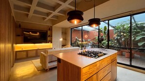 A modern kitchen with a central island, wooden cabinets, and a large window offering a view of the outdoors. - w* | Charming 1BR Apartment w/ Terrace in Laureles (Medellín)