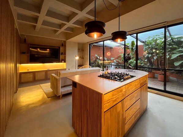 Een moderne keuken met een centraal eiland, houten kastjes en een groot raam met uitzicht op de omgeving.