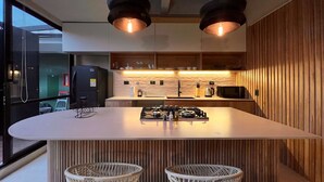 A modern kitchen with a central island, two bar stools, and pendant lighting. - w* | Charming 1BR Apartment w/ Terrace in Laureles (Medellín)
