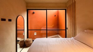 A hotel room with a large bed, a sliding door to a balcony, and two woven baskets on the floor. - w* | Charming 1BR Apartment w/ Terrace in Laureles (Medellín)