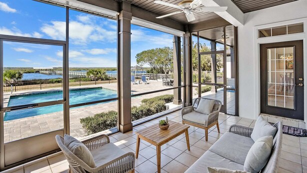 A spacious patio with a view of a swimming pool and a clear blue sky. - Waterfront Home w Patio, Heated Pool, Dock, Beach (St. Augustine)