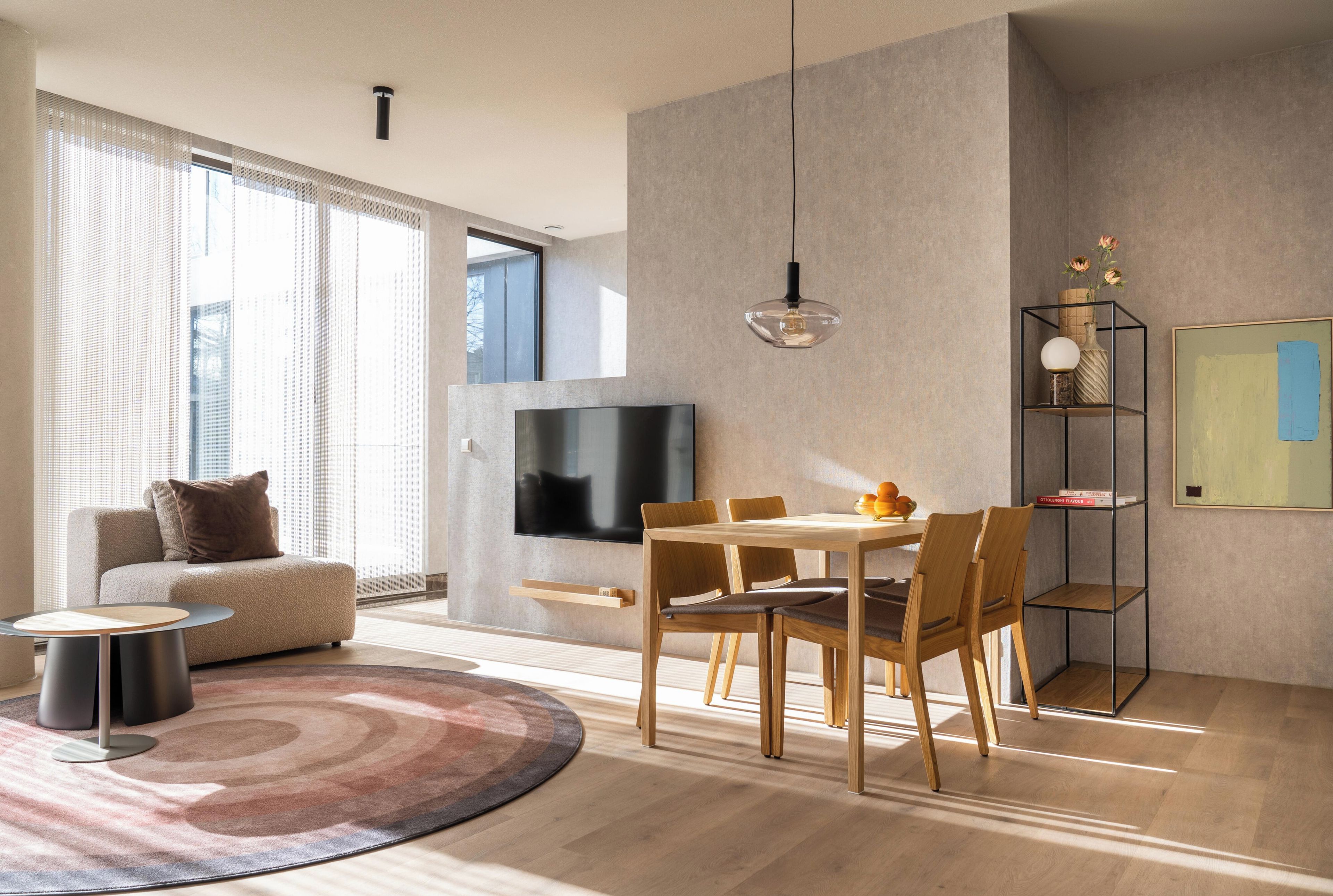 A modern living room with a sofa, TV, dining table, and chairs.