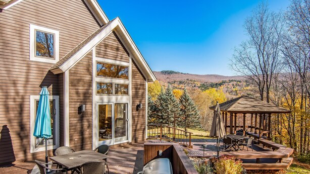 Talo, jossa on terassi, ulkotila istumiseen ja poreallas.