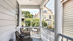 Une véranda couverte avec deux fauteuils en osier et une balustrade blanche.