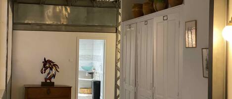 A hallway with a wooden bench, a horse sculpture, and a row of white doors.