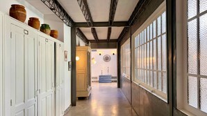 A hallway with white doors, a wooden bench, and a large window with a textured pattern.