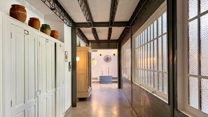 A hallway with white doors, a wooden bench, and a large window with a textured pattern.