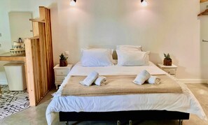Ein ordentlich eingerichtetes Schlafzimmer mit einem Bett, zwei Nachttischen, einer Holzregaleinheit und einer kleinen Mülltonne.