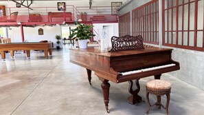 A spacious room with a grand piano, a small stool, and a billiards table.