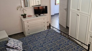Une chambre à coucher avec un lit, une commode, un téléviseur et un lustre.