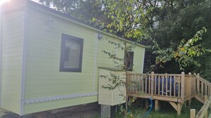 A small, single-story building with a wooden deck and a window. - Glamping Hut - Sleeps 2, hot tub & Parking (Welshpool)