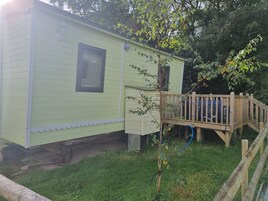 A small, single-story building with a wooden deck and a window.