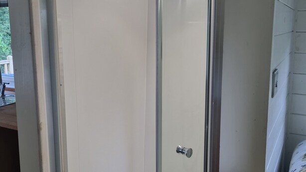 A glass-enclosed shower area with a white tiled floor and a visible showerhead. - Glamping Hut - Sleeps 2, hot tub & Parking (Welshpool)