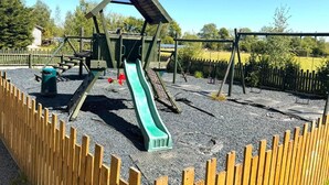 A playground with a slide, climbing structures, and a swing set. - Glamping Hut - Sleeps 2, hot tub & Parking (Welshpool)