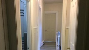 A narrow hallway with a wooden floor leading to a door at the end. - Henderson Héritage Home (Ottawa)