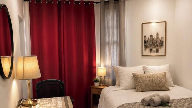 A hotel room with a bed, a desk, a chair, a lamp, a bedside table, and a wall-mounted picture. - Henderson Héritage Home (Ottawa)