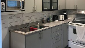 A modern kitchen with grey cabinets, a built-in microwave, a stainless steel sink, and a stove. - Henderson Héritage Home (Ottawa)