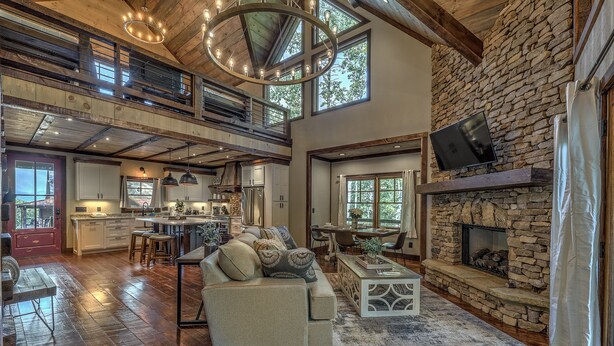 A spacious living area with a stone fireplace, a sofa with cushions, and a dining area.