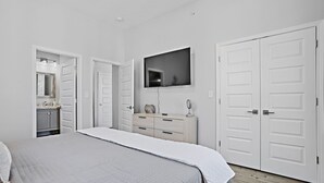 Ein Schlafzimmer mit Bett, Kommode, Fernseher und Kleiderschrank.