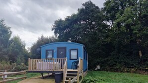 A blue mobile home with a wooden deck, a small porch, and a single door. - Glamping Hut - Sleeps up to 4 Hot Tub & Parking (Welshpool)
