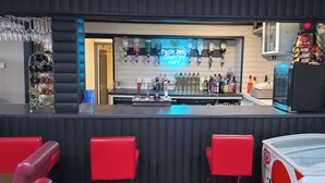 A bar area with multiple beverage dispensers, a neon sign, and red seating. - Glamping Hut - Sleeps up to 4 Hot Tub & Parking (Welshpool)