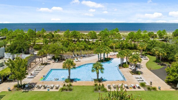 A resort with a large pool, lounge chairs, and a view of the ocean. - WaterView • NEW Boardwalk to Beach • Sleeps 15 • Resort Pools (Port St. Joe)
