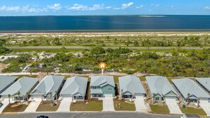 A coastal residential area with multiple houses, a clear view of the ocean, and a road leading to the beach. - WaterView • NEW Boardwalk to Beach • Sleeps 15 • Resort Pools (Port St. Joe)