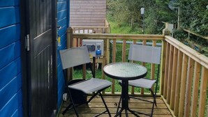 Una terraza de madera con una mesa redonda de vidrio y dos sillas.
