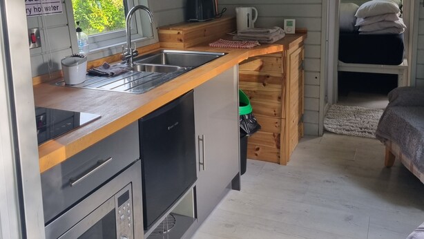 A compact kitchen with a sink, stove, and wooden cabinets. - Glamping Hut - Sleeps 2, hot tub & Parking (Welshpool)