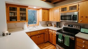 A kitchen with wooden cabinets, a stainless steel oven, a microwave, and a sink.