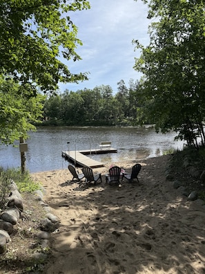 Un cadre idyllique au bord du lac, avec un quai, des chaises et une plage de sable.
