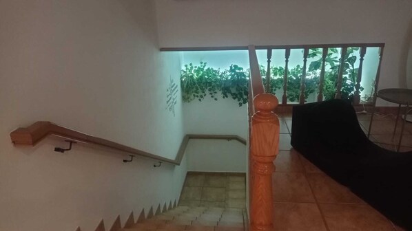 A staircase with a wooden handrail and a black chair in the foreground. - A Morada de Julia (Morgadans-Gondomar)