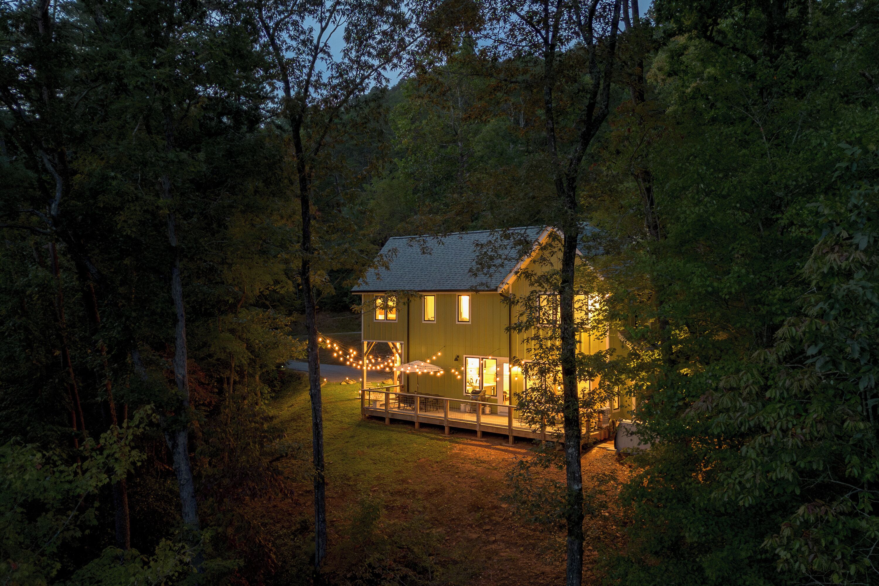 Ein Haus, umgeben von Bäumen, mit einer Veranda und Lichterketten.
