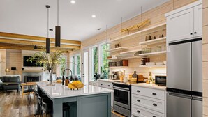 Une cuisine moderne dotée d’un îlot central, d’appareils électroménagers intégrés et de meubles de rangement en bois.