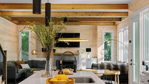 Une cuisine moderne avec un îlot central, des poutres en bois et une grande fenêtre.