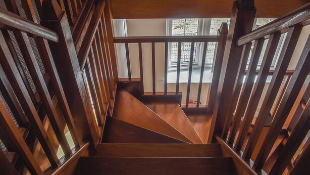 A wooden staircase with a handrail, leading to a landing with a window. - The Coach House - UK41070 (Wootton, near Ryde)