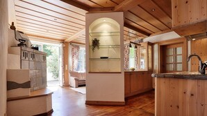 A spacious kitchen with wooden floors, a central island, and a glass-fronted shelving unit. - Landhotel Schwab Ferienhaus (Schwarzach am Main)
