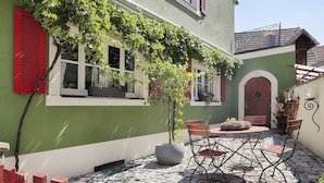 A courtyard with a stone floor, a table with chairs, and a potted plant. - Landhotel Schwab Ferienhaus (Schwarzach am Main)
