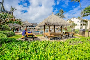 Relax by the pool surrounded by lush greenery and shaded seating areas.