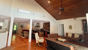 Un amplio salón con techo alto y vigas de madera, un comedor con candelabro y una cocina con electrodomésticos modernos.